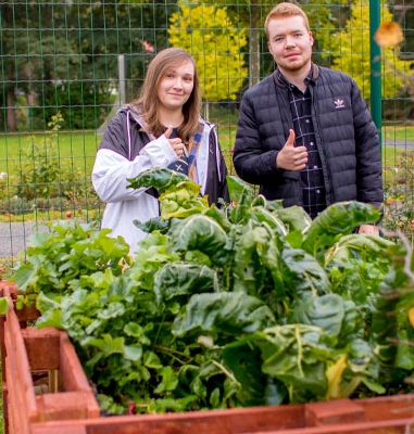 Die Azubis Antonia und Rico vor dem selbstgebauten Hochbeet