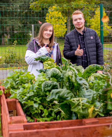 Die Azubis Antonia und Rico vor dem selbstgebauten Hochbeet