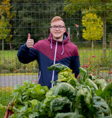 Der Azubi Marvin vor dem selbstgebauten Hochbeet