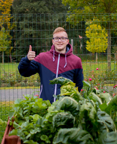 Der Azubi Marvin vor dem selbstgebauten Hochbeet
