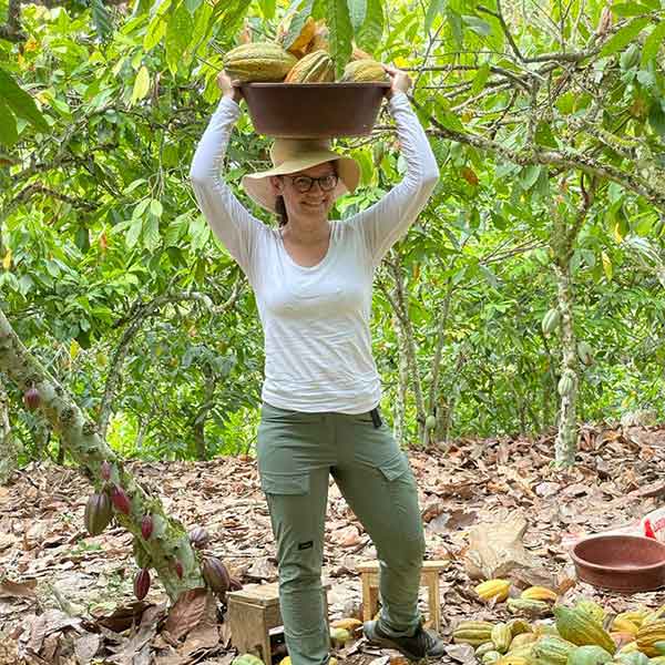 Ariane-auf-Kakao-Plantage Ariane Schmidt trägt frisch geerntete Kakaofrüchte auf dem Kopf