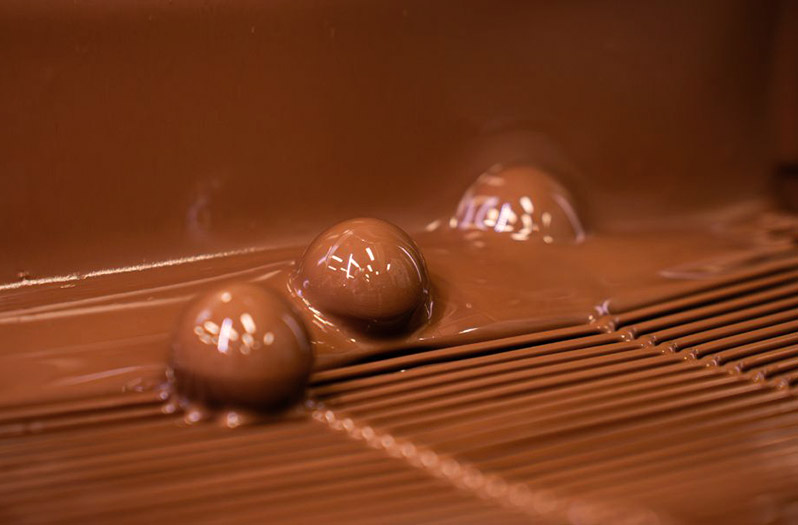 Pralinen Herstellung flüssige Schokolade Pralinen werden von flüssiger Schokolade überzogen